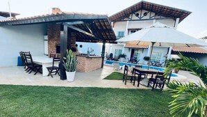 Eine Terrasse mit Gartenmöbeln, einer Ziegelstruktur und einem Swimmingpool.