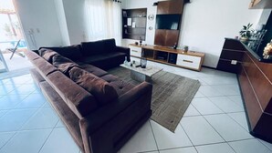 Ein modernes Wohnzimmer mit braunem Sofa, Couchtisch, Fernseher und Schrank.