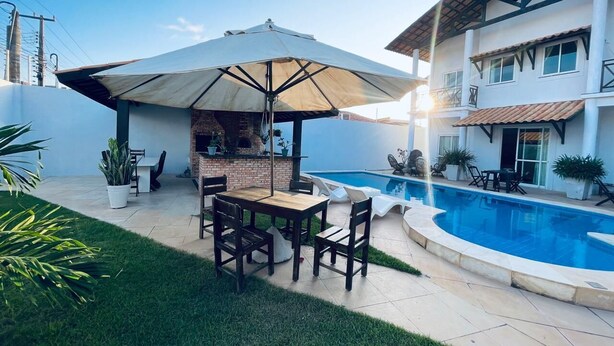 Ein Garten mit Pool, Grillplatz und Essgruppe.