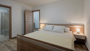 Ein modernes Schlafzimmer mit einem hölzernen Bett, Nachttischlampen und einer Duschkabine aus Glas.