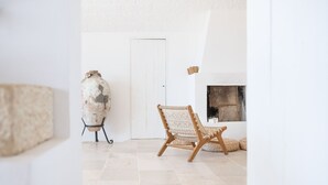 A room with a white door, a wicker chair, and a large pot on a stand.