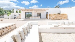 A modern outdoor living area with a covered patio, outdoor seating, and a stone wall.