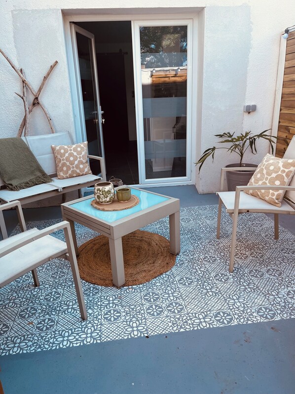A patio area with a table, chairs, a bench, and a potted plant.