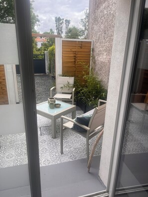 A patio with a table and chairs, a wooden fence, and potted plants.