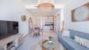 A modern living room with a TV, sofa, and dining area. - Czechin - Signature Livings (Madinat Zayed)