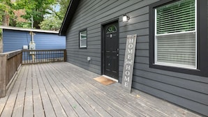 A wooden deck leading to a dark gray house with a black door and a 'HOME' sign. - 2 bedroom Rustic Duplex-Free Parking (Lithia Springs)