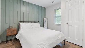 A bedroom with a bed, a nightstand, a dresser, and a door. - 2 bedroom Rustic Duplex-Free Parking (Lithia Springs)