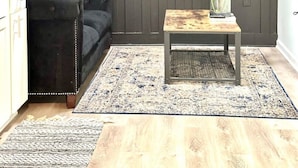 A room with a dark wooden wall, a black leather sofa, a small wooden table with a vase of flowers, and a patterned rug. - 2 bedroom Rustic Duplex-Free Parking (Lithia Springs)