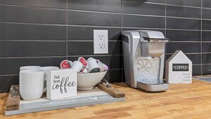 Una estación de café con cafetera, tazas y un cartel que dice 'Welcome to the Coffee House'.