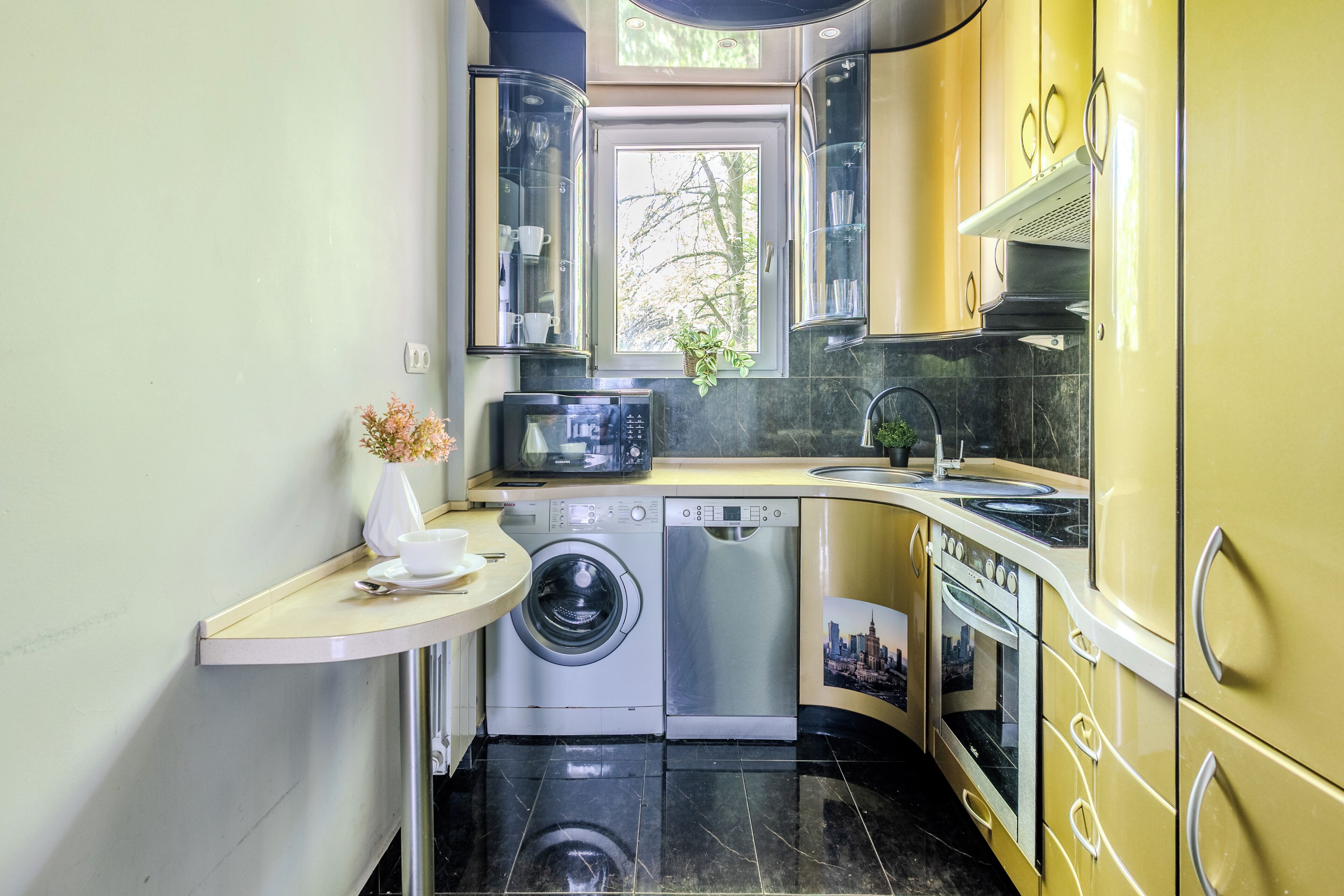 A compact kitchen with a washing machine, microwave, and sink.