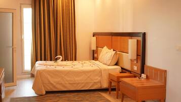 Una habitación de hotel con una cama, una mesita de noche y una pequeña silla de madera.