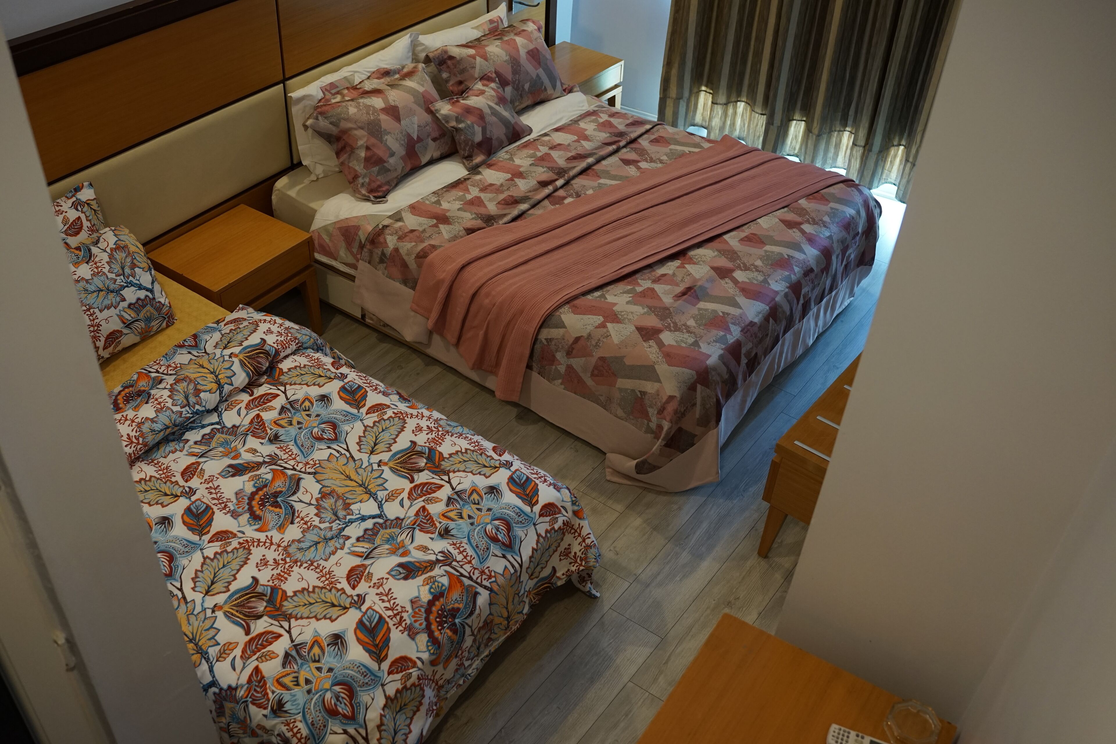 A bedroom with two beds, each with patterned bedding and a wooden headboard.