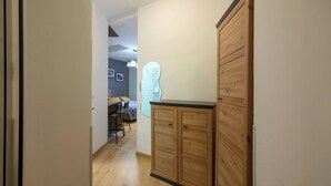 A hallway with wooden cabinets, a dining area with chairs and a table, and a wall with a light fixture. - Vera Studio Deluxe With Oldtown View (Zadar)