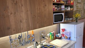 Eine Küche mit Holzausstattung, einer Mikrowelle, einem Kühlschrank und verschiedenen Lebensmitteln auf der Arbeitsfläche.