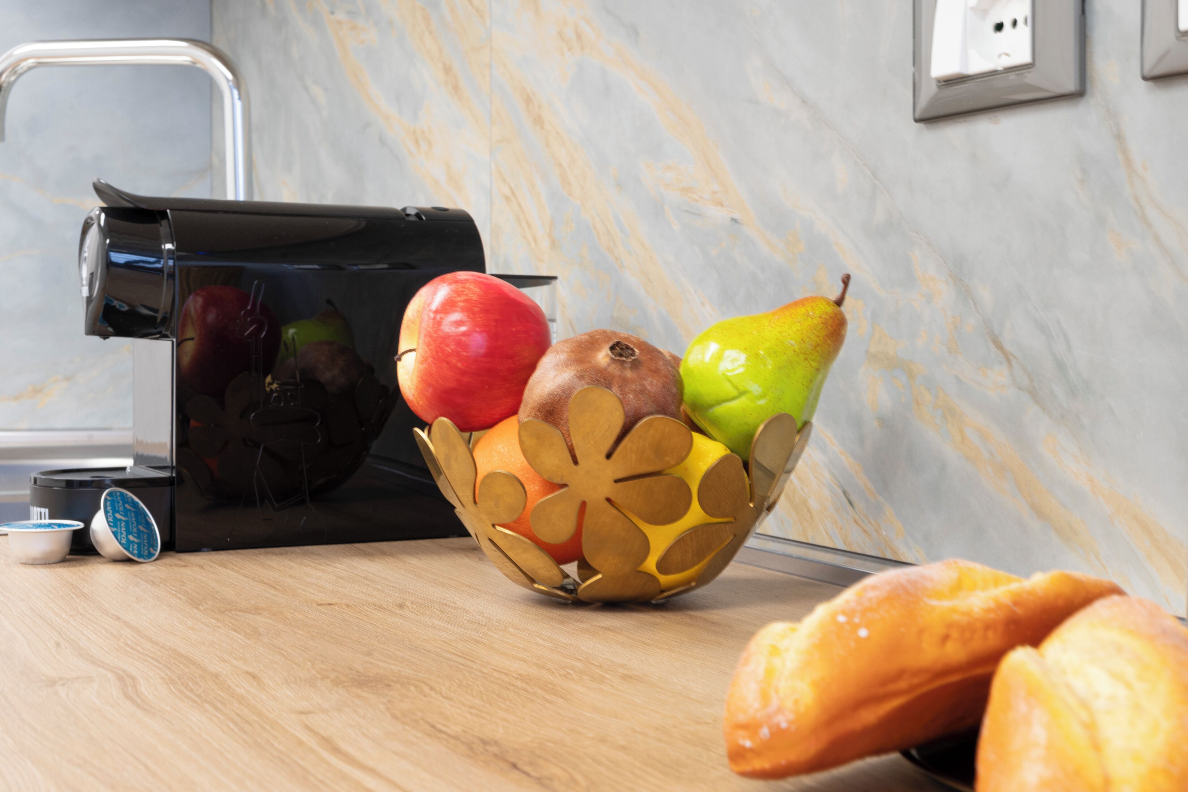 Un plan de travail de cuisine avec un panier de fruits contenant des pommes et une poire, un grille-pain et une miche de pain.