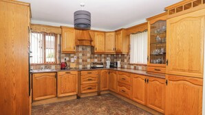 A kitchen with wooden cabinets, a tiled floor, and a built-in stove.