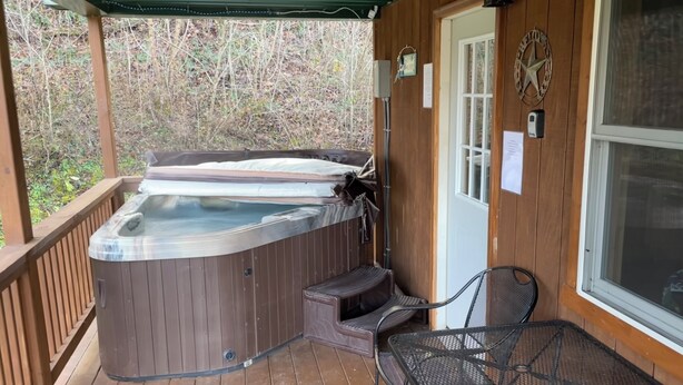 A wooden deck with a hot tub, a covered seating area, and a door with a star emblem. - Lowry’s Retreat (South Bloomingville)