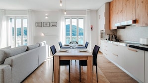 Een moderne keuken met houten kasten, een eettafel gedekt voor zes personen, en uitzicht op de bergen door grote ramen.