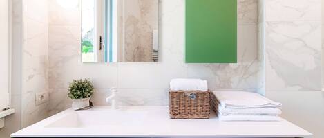 A modern bathroom with a white sink, a green cabinet, a Bosch washing machine, and a mirror with a green accent wall.