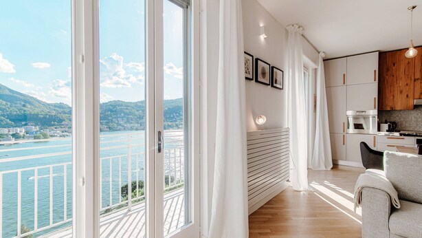 Een moderne woonkamer met een grote schuifpui die uitkomt op een balkon met uitzicht op een rivier.
