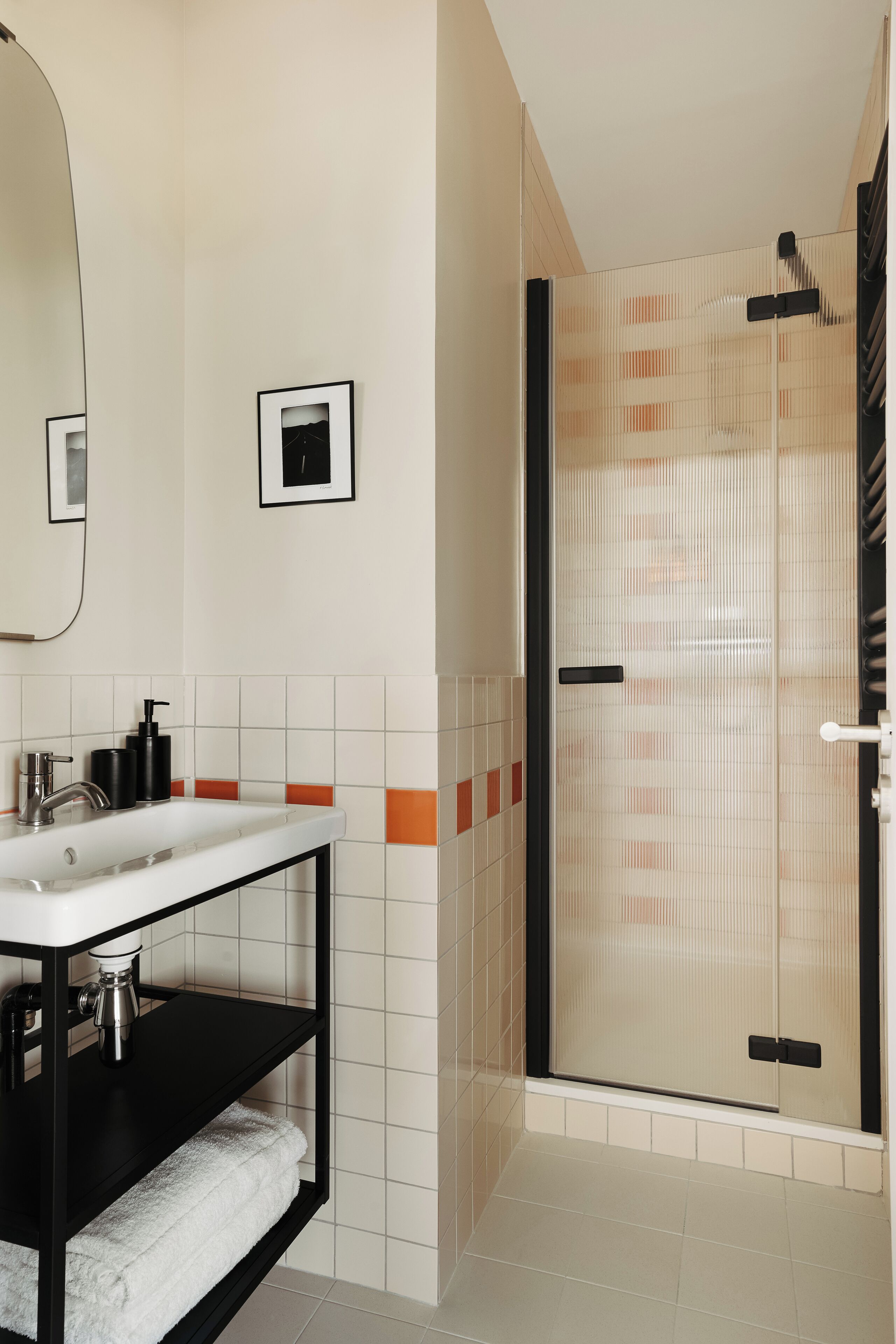Une salle de bain moderne avec une douche à parois de verre, un lavabo blanc et un meuble-lavabo noir.
