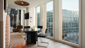 A modern dining area with a round table, black chairs, and a patterned sofa. - Edgar Suites Lille - Shake  (Lille)