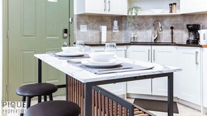 A modern kitchen with white cabinets, a marble countertop, and a green door. - Spacious Bright  - Sleep 2 - Long Stays - NFLX&WIFI (Edmonton)