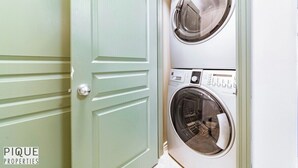 A laundry room with two stacked front-loading washing machines and a light green door. - Spacious Bright  - Sleep 2 - Long Stays - NFLX&WIFI (Edmonton)