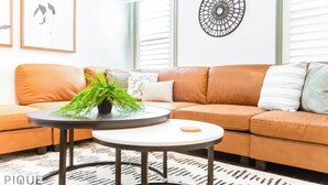 A modern living room with a sofa, a round coffee table, and a decorative wall piece. - Spacious Bright  - Sleep 2 - Long Stays - NFLX&WIFI (Edmonton)