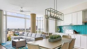 A modern apartment with a living room, dining area, and kitchen. It features large windows, a ceiling fan, and a view of the city. - Atlanta Margaritaville 2 Bedroom Deluxe! (Atlanta)