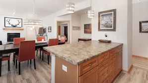 Eine moderne Küche mit Granit Arbeitsplatten, Holzschränken und Pendelleuchten.
