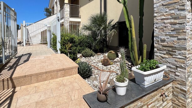 A residential building with a stone facade, a balcony, and a well-maintained garden with various cacti and succulents. - Welcome to Villa Lodo - The Perfect Retreat for Couples   (Sicilia)