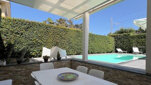 A patio with a table and chairs, a pool, and a hedge. - Welcome to Villa Lodo - The Perfect Retreat for Couples   (Sicilia)