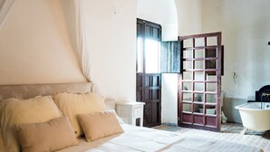 Une chambre à coucher avec un grand lit, une porte en bois et une baignoire.