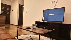 A modern living room with a wooden coffee table, a television displaying YouTube, a dark wooden cabinet, and a brown leather sofa. - Modern apartment in Recoleta (Cochabamba)
