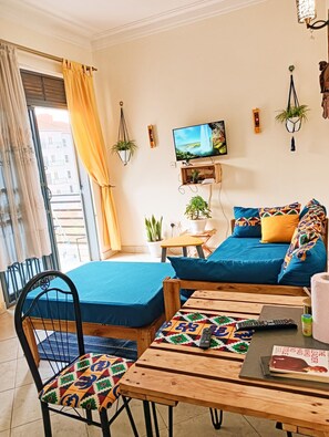 Una sala de estar con un sofá, una silla, una mesita y un televisor en la pared.