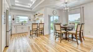 A modern kitchen with wooden flooring, white cabinetry, and a dining area with a chandelier. - Charming 3-bedroom Relaxing Family Vacation Retreat On The Water,  Fishing (Rotonda West)