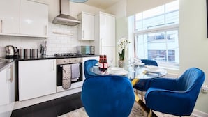 Una cocina moderna con armarios blancos, encimera negra y una silla azul.