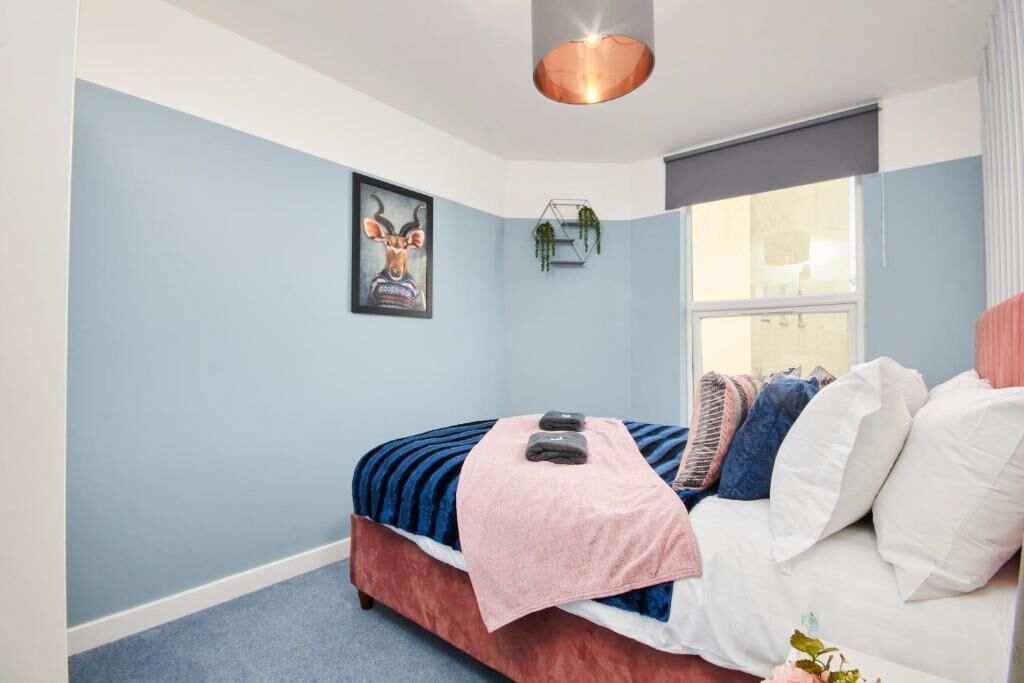 Une chambre à coucher avec un lit, une fenêtre, une plante fixée au mur et un luminaire au plafond.