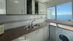 A kitchen with white cabinets, a double sink, and a washing machine. - TERRASOL FRONTAL AL MAR ANTILLAS 8 (Torre del Mar)