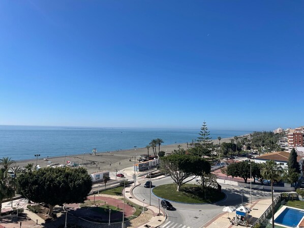 Vista costera con playa, palmeras y una glorieta.
