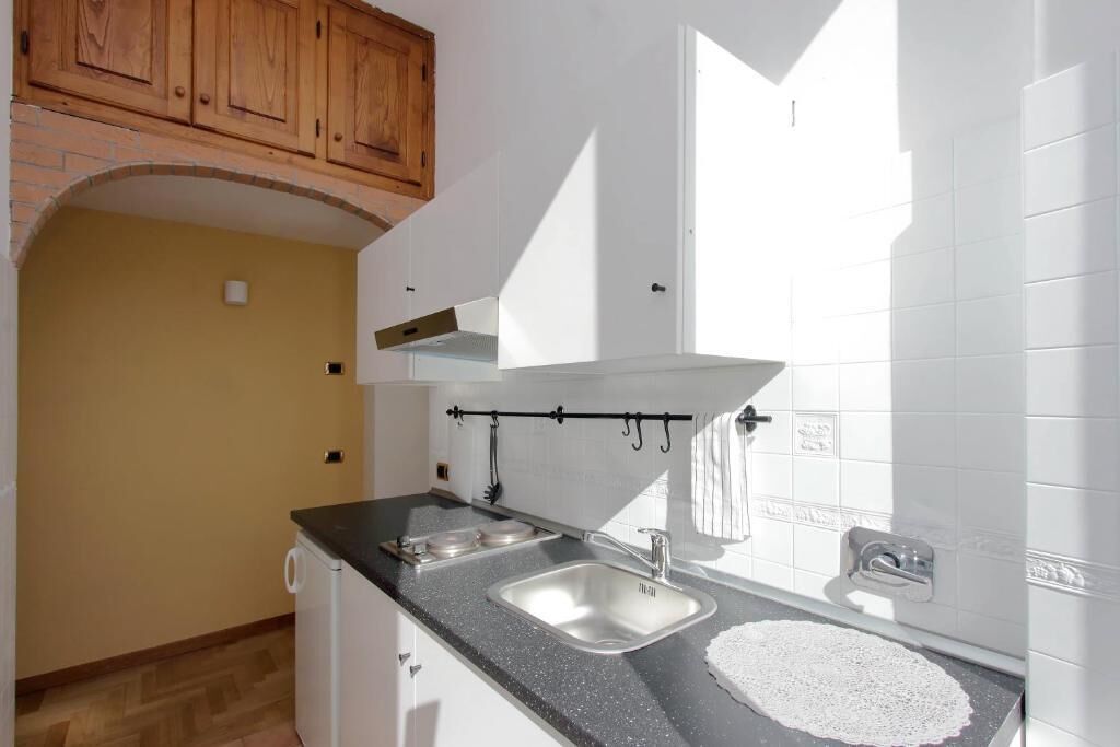 A kitchen with a black countertop, two sinks, and wooden cabinets.