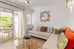 En stue med sofa, et rundt spejl og et spisebord med stole.