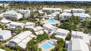 A resort with multiple buildings, a central swimming pool, and surrounding greenery.