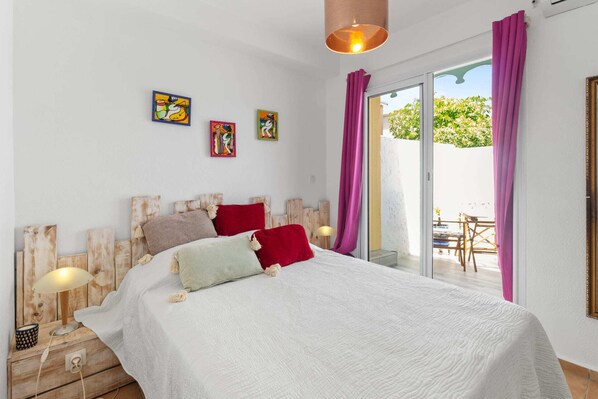 A bedroom with a bed, pillows, a nightstand, a lamp, and artwork on the wall.
