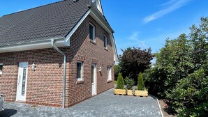 Ett tvåvåningshus byggt av tegel med ett sluttande tak, en satellantenn och en asfalterad uppfart.