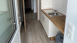 A narrow kitchen with a wooden countertop, white cabinets, and a stainless steel sink. - Country house Hassel 1  (Wiefelstede)