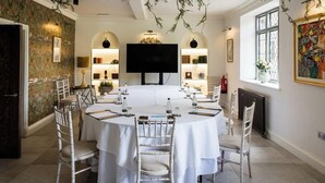 A conference room with a large table, white chairs, and a television screen. - Weston Manor (Bicester)