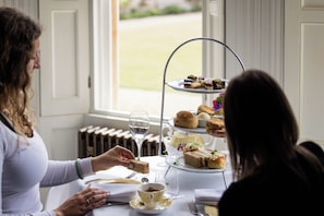 A table set for a tea service with a tiered dessert stand, a teapot, and a cup of tea. - Weston Manor (Bicester)