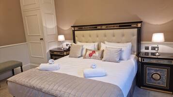 A neatly arranged bedroom with a large bed, two bedside tables, a bench, and a door.